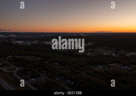 Vue aérienne par drone sur le quartier forestier et les bâtiments industriels éloignés près de Truro Nouvelle-Écosse Canada pendant le coucher du soleil avec horizon et pois brillants Banque D'Images