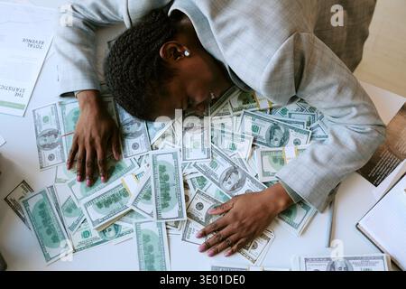 Jeune adulte femme noire souriante tout en étant allongée sur la table couverte d'argent Banque D'Images