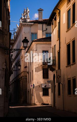 Ombres profondes et lumière dorée de l'après-midi sur des façades historiques de couleur crème avec statues classiques sur un toit à Vicence, Italie 08.01.2026 Banque D'Images
