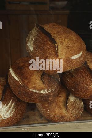 Pains au levain artisanaux empilés dans un présentoir de boulangerie, présentant une texture croustillante fraîche et une délicieuse croûte dorée chaude. Cotswolds, Engl Banque D'Images