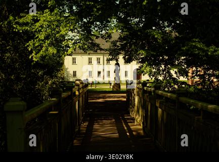Domaine serein avec pont ombragé. Pont en bois rustique menant à Estate Under Canopy à Moody Light Banque D'Images