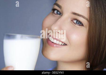Bonne jeune femme avec un verre de lait ou de lait de protéine shake, boisson de cocktail saine pour le régime et le concept de bien-être Banque D'Images