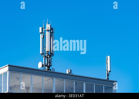 Deux tours de télécommunication se dressent au sommet d'un bâtiment sous un ciel bleu clair. Les tours sont des équipements utilisés pour les réseaux mobiles et les signaux, montrant Banque D'Images