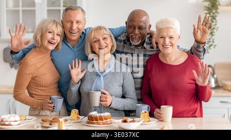 Les amis se réunissent pour une joyeuse célébration avec gâteaux et boissons dans un cadre de cuisine confortable Banque D'Images