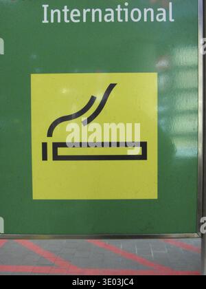Signe jaune de zone fumeurs sur un fond vert, dans l'espace public Banque D'Images
