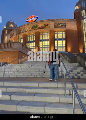 Homme avec une canne montant un grand escalier extérieur vers la Dickies Arena à Fort Worth, Texas, illuminé au crépuscule Banque D'Images