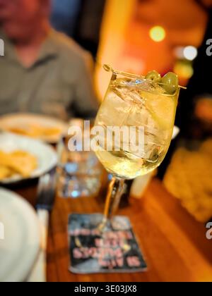 Gros plan d'un cocktail rafraîchissant garni d'olives vertes sur un bâton servi dans un bar ou un restaurant faiblement éclairé Banque D'Images