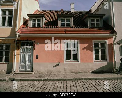 Bâtiment résidentiel historique rose avec le numéro 30 sur la porte et un toit de tuiles rouges le long d'une rue pavée dans la vieille ville de Tallinn, Estonie. Banque D'Images