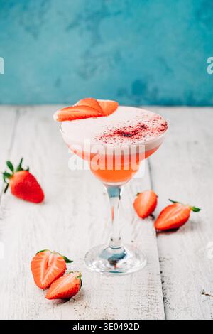 Un cocktail de fraises magnifiquement conçu se tient gracieusement dans un verre à martini. Cette boisson rafraîchissante, garnie de fraises fraîches, vous invite Banque D'Images