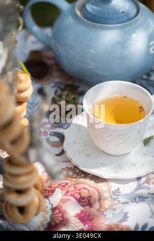 Une installation raffinée de thé avec une délicate tasse en porcelaine remplie de thé chaud, un samovar traditionnel et une pile de baranki croquants, serrés contre un colo Banque D'Images