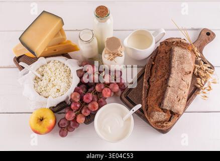 Un assortiment de produits laitiers, de fruits frais et de pain sur une table en bois, représentant les aliments traditionnels appréciés pendant la fête juive de Shavuo Banque D'Images