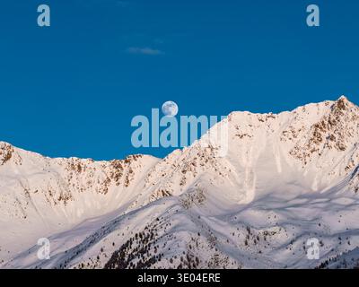 Crépuscule aérien au-dessus des Dolomites italiennes avec pleine lune et alpenglow Banque D'Images