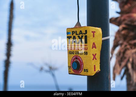 Antalya, Turquie - 24 décembre, 2022 - bouton d'appel de taxi jaune monté sur le poteau de rue utilisé pour demander un service de taxi dans la rue de la ville turque avec Palm tre Banque D'Images