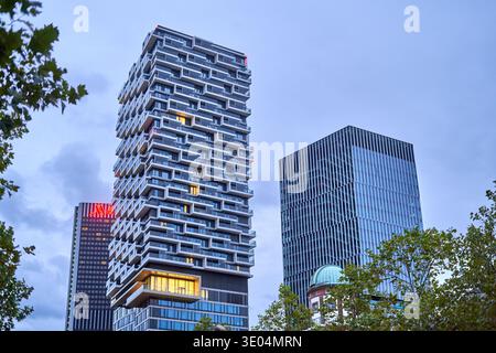 Tour résidentielle moderne de grande hauteur avec balcons géométriques empilés distinctifs illuminés au crépuscule à Francfort, en Allemagne. Le contemporain... Banque D'Images