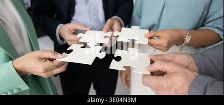 Fermez diverses mains de gens d'affaires tenant des pièces de puzzle se connectant ensemble Banque D'Images