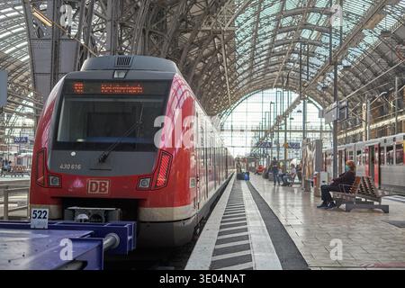 Un train de banlieue rouge Deutsche Bahn (DB) se trouve à un quai à l'intérieur de la gare principale de Francfort (Hauptbahnhof) en Allemagne. Le train moderne,... Banque D'Images