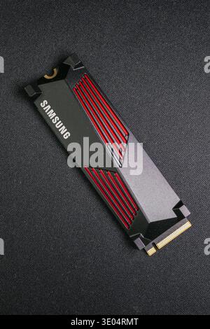Gros plan d'un lecteur Samsung NVMe SSD M.2 PCIe haute performance doté d'ailettes de refroidissement rouges et d'un design noir élégant, isolé sur une surface texturée sombre Banque D'Images