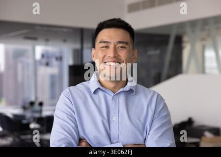 Jeune homme d'affaires asiatique confiant posant pour un portrait de tête au bureau Banque D'Images
