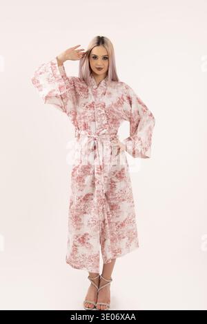 Femme en robe florale posant avec la main dans les cheveux Banque D'Images