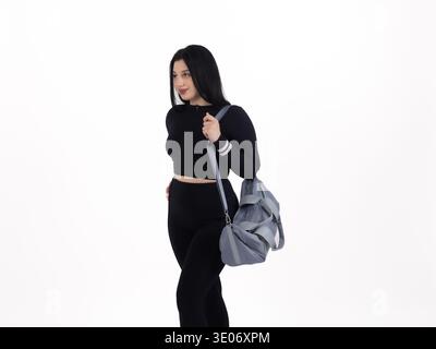 Femme dans des vêtements d'entraînement noirs portant un sac Banque D'Images