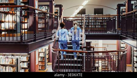 Médecine, étudiants et femmes dans la bibliothèque pour l'éducation, l'apprentissage et les filles marchent dans les escaliers à l'université. Université, infirmières et amis en marche pour Banque D'Images