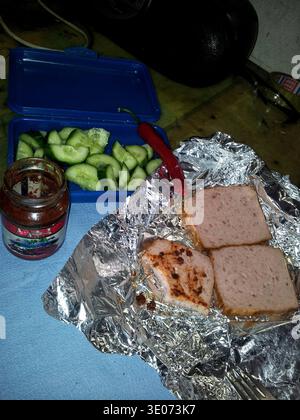 Sandwich avec tranches de concombre sur feuille, déjeuner rustique avec pot ouvert relish, tranches de concombre dans un récipient en plastique, deux tranches de pain reposant sur Banque D'Images