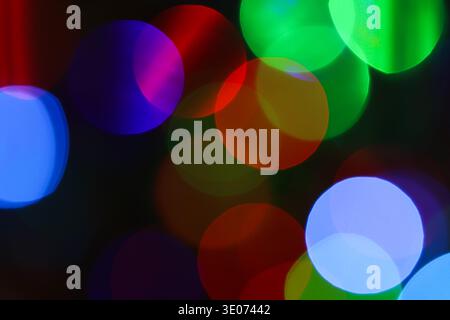 Une image floue de lumières colorées avec un cercle violet et vert au milieu. L'image a une humeur rêveuse et fantaisiste Banque D'Images