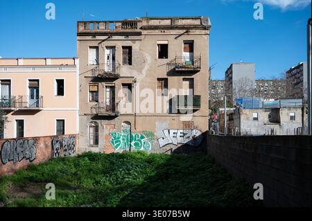 Immeuble résidentiel abandonné de trois étages avec graffitis et un terrain de jardin négligé dans une zone urbaine de Barcelone. Banque D'Images