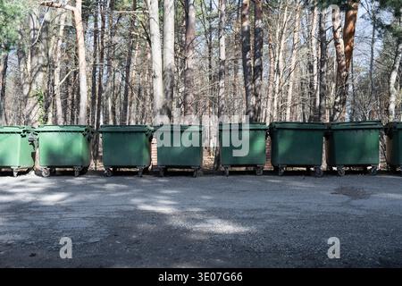 Rangée de poubelles vertes dans un parc forestier. Concept de gestion des déchets et de protection de l'environnement dans les zones récréatives. Grands déchets plastiques conta Banque D'Images
