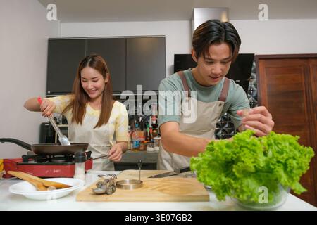 Asiatique jeune couple cuisinant dans la cuisine à la maison Banque D'Images