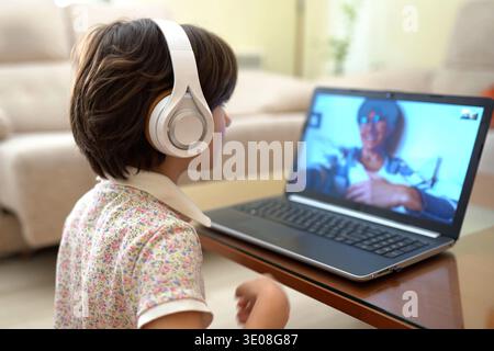 Adolescent se concentre sur la session de classe numérique dans le cadre confortable du salon Banque D'Images