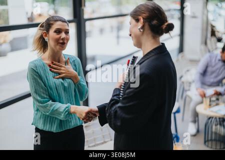Deux femmes d'affaires se serrant la main lors d'une réunion de collaboration amicale dans un café de bureau moderne Banque D'Images
