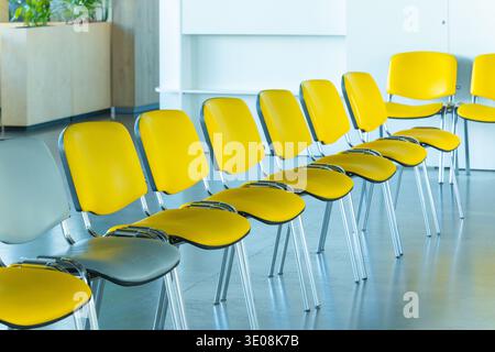 La disposition moderne des sièges est agrémentée de chaises jaunes vives et grises discrètes, ce qui en fait un espace contemporain idéal pour les réunions ou les attentes du public Banque D'Images