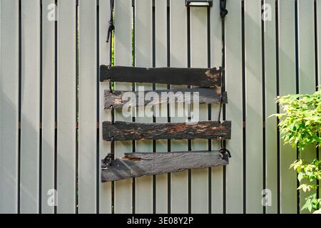 Ensemble de panneau en bois vieilli accroché contre une clôture grise dans le jardin Banque D'Images