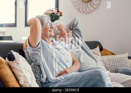 Paisible homme d'âge moyen et femme avec les yeux fermés se relaxant sur un canapé confortable à la maison, famille mature rêvant ensemble, femme aux cheveux gris et hu Banque D'Images