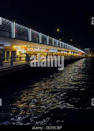 Photo de nuit latérale du pont de Galata sur la Corne d'Or, montrant l'agitation dans la soirée ; Karaköy peut être vu en arrière-plan, Istanbul Banque D'Images