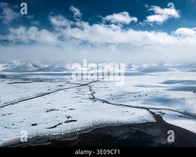 Vue aérienne de la neige couverte sur le plateau d'Arabel avec lac alpin gelé et vaste paysage d'hiver, chaîne de montagnes enneigées au Kirghizistan Banque D'Images