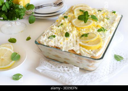 Tiramisu citron italien. Tiramisu citron avec coccinelles et crème mascarpone sur une table blanche, décoration menthe fraîche. Dessert d'été. Directement au-dessus. Banque D'Images