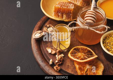 La collection de miel, de noix et de fruits séchés sur une planche en bois est prête pour une expérience sucrée Banque D'Images