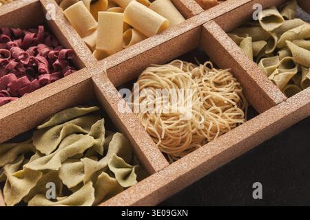 Collection de différents types de pâtes disposées dans un plateau en bois pour la cuisson ou l'affichage Banque D'Images