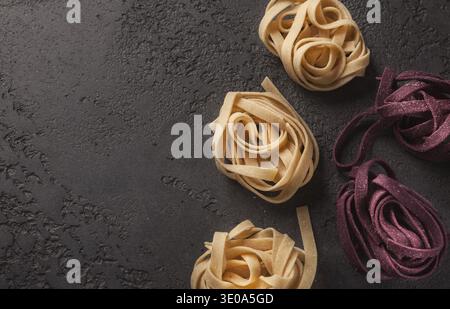 Différents types de pâtes disposées sur une surface sombre dans des lots soignés pour la préparation de la cuisson Banque D'Images