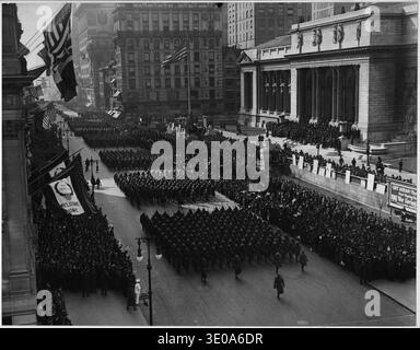 Défilé du 369e régiment d'infanterie sur la Cinquième Avenue, New York, 1919. La photographie montre le célèbre régiment afro-américain basé à Harlem, connu sous le nom de « Hell Fighters », marchant devant la bibliothèque publique de New York, à la 42e Rue et à la Cinquième Avenue. Dirigé par le colonel William 'Bill' Hayward, le défilé célébrait le retour du régiment de la première Guerre mondiale, où ils se sont distingués pour leur bravoure et leurs performances au combat en France. L'événement a attiré de grandes foules et faisait partie d'une reconnaissance plus large des contributions militaires afro-américaines, reflétant à la fois la célébration patriotique et la dyna raciale Banque D'Images