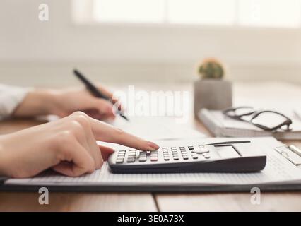 Gros plan de la main de femme comptant sur la calculatrice Banque D'Images