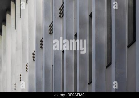 Architecture moderne, gros plan architectural d'ailettes blanches verticales sur une surface gris foncé, contrastant avec un motif de grille horizontale. Minimaliste moderne Banque D'Images