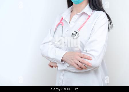 Médecin féminin confiant portant un masque médical avec stéthoscope et bras croisés, portrait professionnel de la santé représentant la confiance dans la médecine Banque D'Images