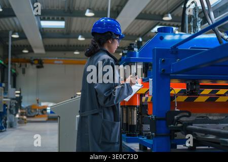 Une ingénieure industrielle indienne effectue l'inspection de l'équipement et le contrôle de la qualité dans un environnement de fabrication axé sur la sécurité. Banque D'Images