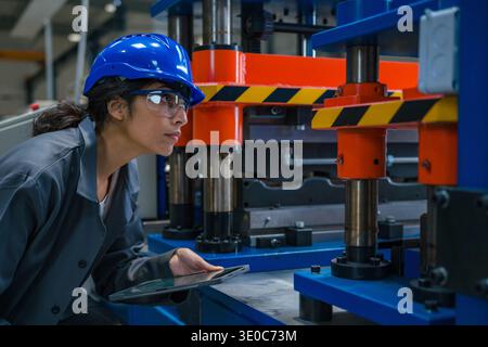 Une ingénieure industrielle indienne effectue une inspection détaillée de l'équipement dans une usine de fabrication moderne pour le contrôle de la qualité. Banque D'Images