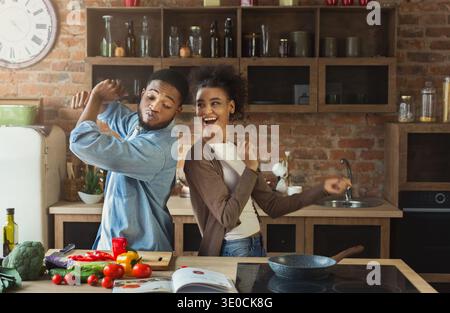 Couple noir dansant près de la table avec de la nourriture dans la cuisine Banque D'Images