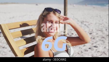Femme couchée dans un haut de bikini léger, lunettes de soleil bronzant sur un salon à lattes à la plage de sable, 6G. Banque D'Images