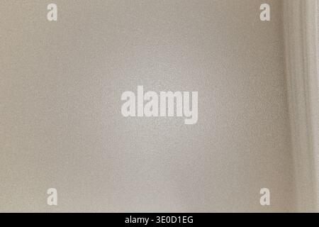 L'image montre un mur Uni, beige clair ou blanc cassé avec une texture légèrement floue. Il y a une légère marque ou une décoloration à peine visible près de th Banque D'Images